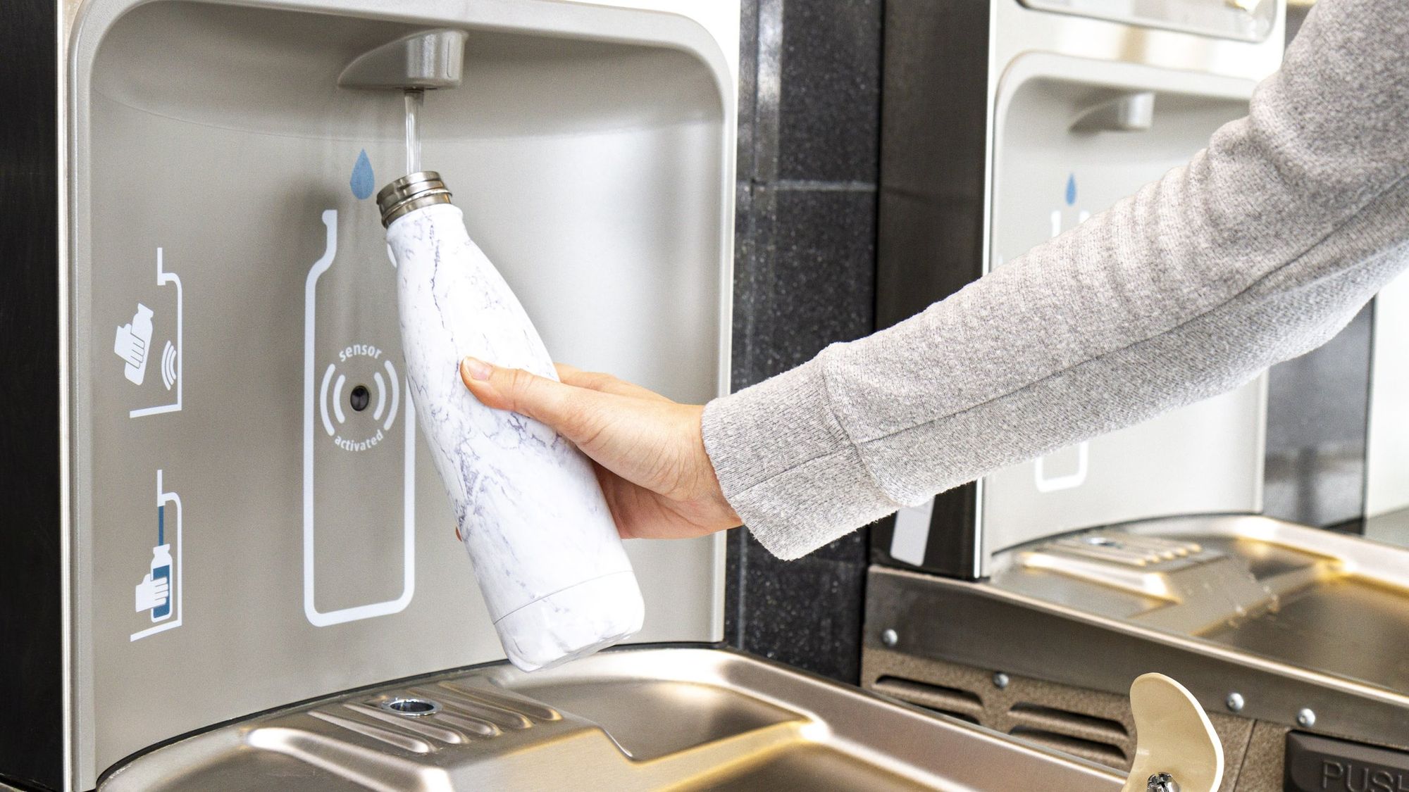 Reusable bottle being filled at a bottle-filling water station